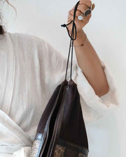 Person holding a black drawstring bag against a white background