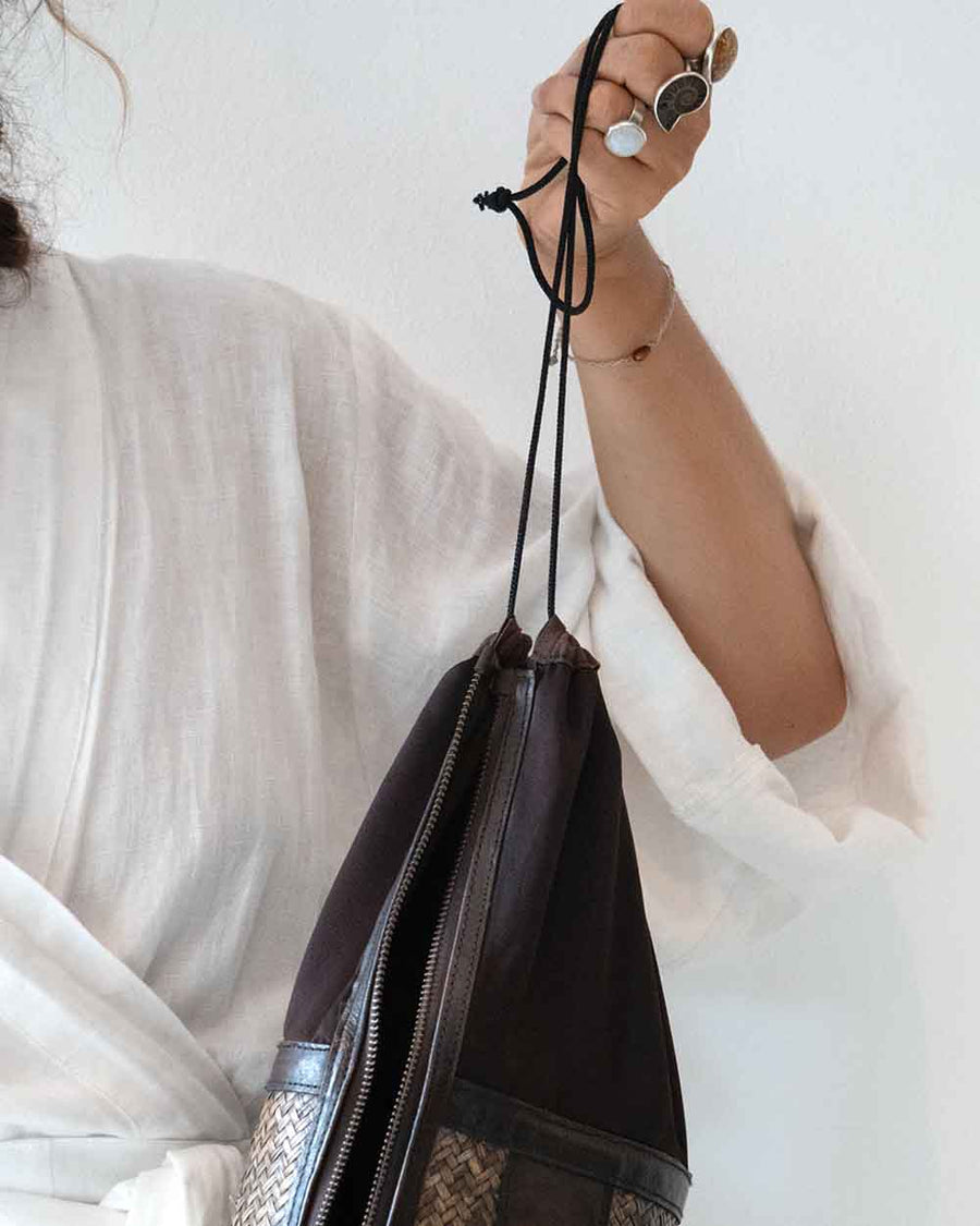 Person holding a black drawstring bag against a white background