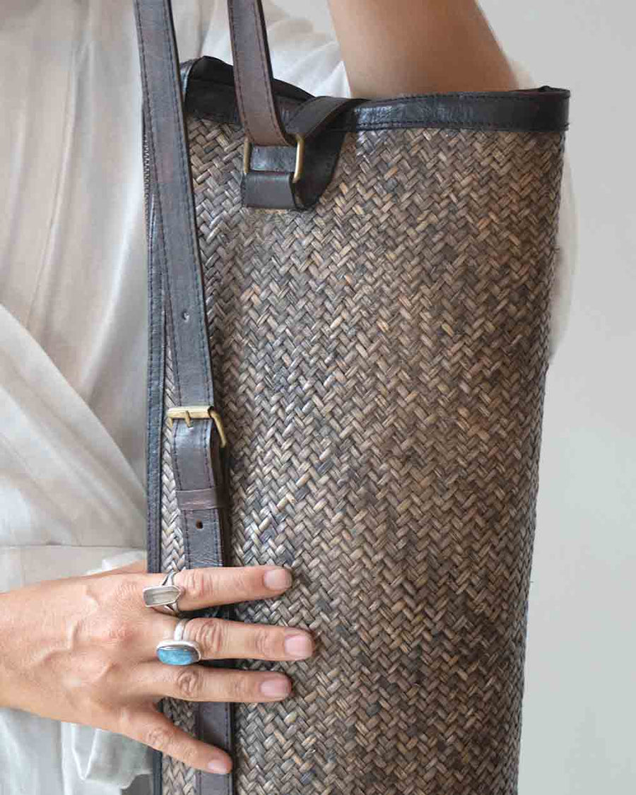 Person holding a woven bag with a plain background